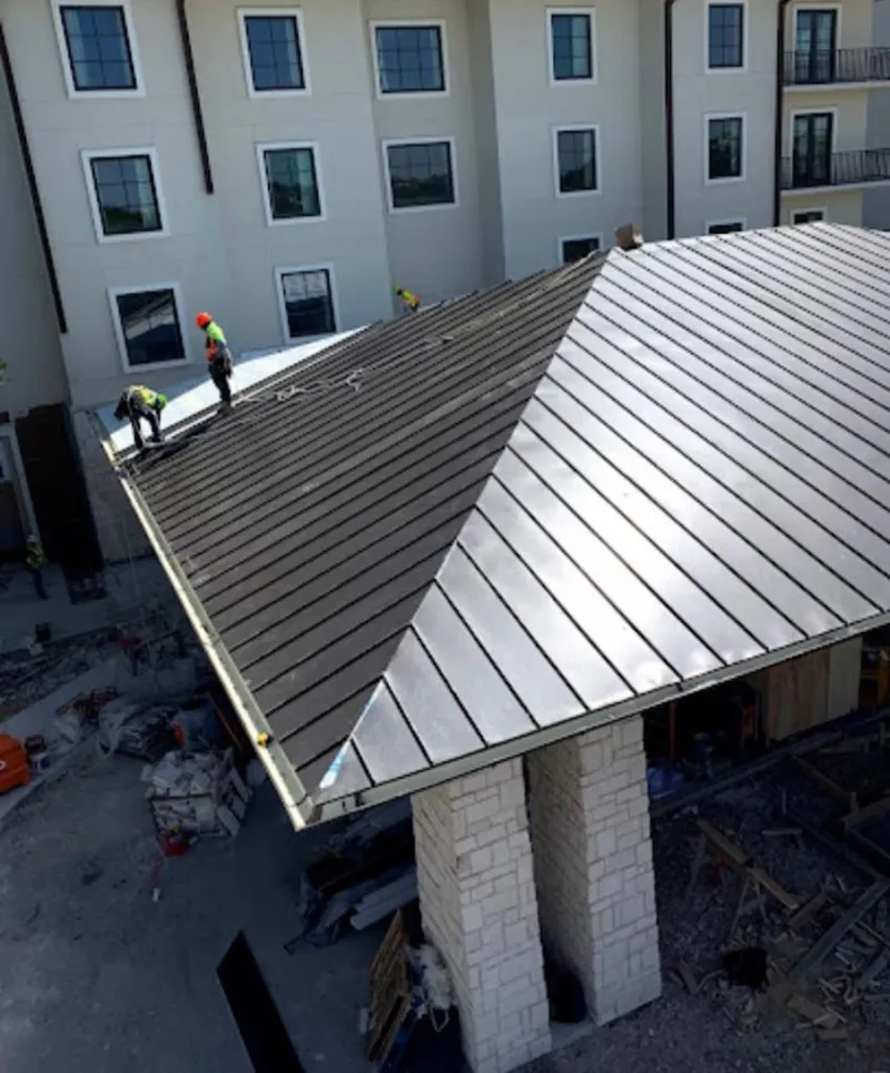 Crew installing standing seam metal roof panels on a commercial project in Swannanoa